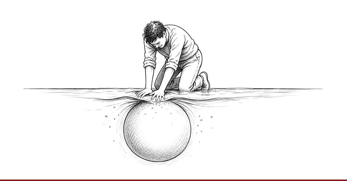 Eine Hand drückt einen Ball unter die Wasseroberfläche, der mit aller Kraft nach oben zurückdrängt.